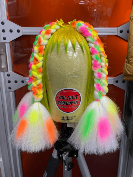 A braided neon wig on a mannequin head in the trailer for the show Margo's Got Money Troubles.
