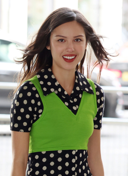 Olivia Rodrigo wearing a black and white polka dot dress and green vest